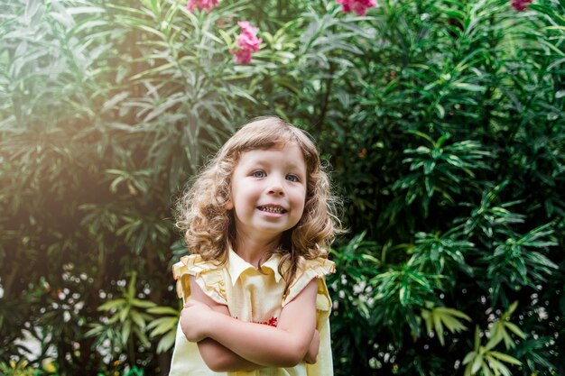 Niña muy feliz en un vestido amarillo en el hermoso jardín verde al aire libre