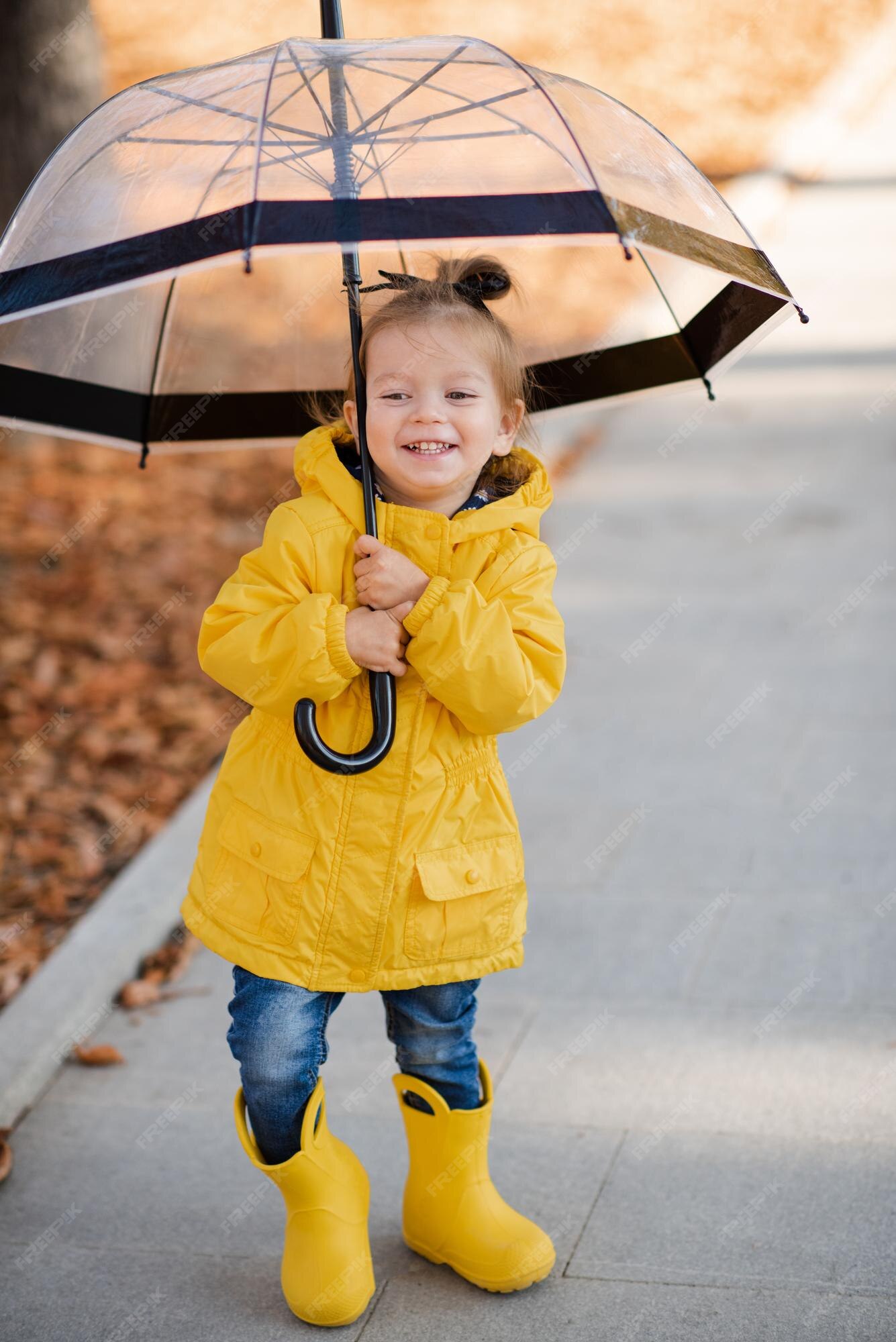 Una niña muy graciosa de años usa botas de goma impermeables amarillas brillantes y camina con paraguas en el parque sobre hojas caídas aire temporada de otoño niño feliz