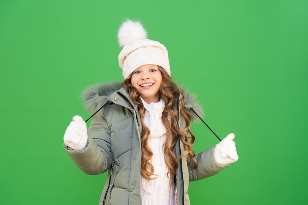 Una niña muy hermosa con el pelo rizado en ropa de abrigo de invierno. ropa de invierno para niños para caminar en las calles. | Foto