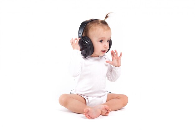 niña muy linda en pijamas blancos con auriculares en la cabeza