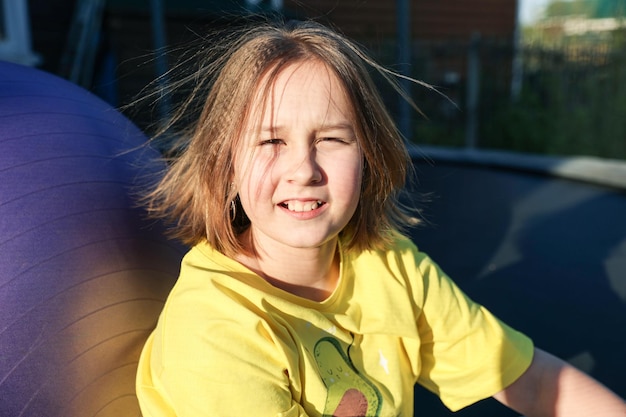 Niña muy sonriente sentada en el trampolín