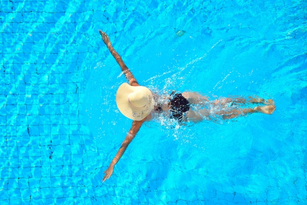 Una niña nada en la piscina. relájate en un hotel con piscina. disfrute de la natación.