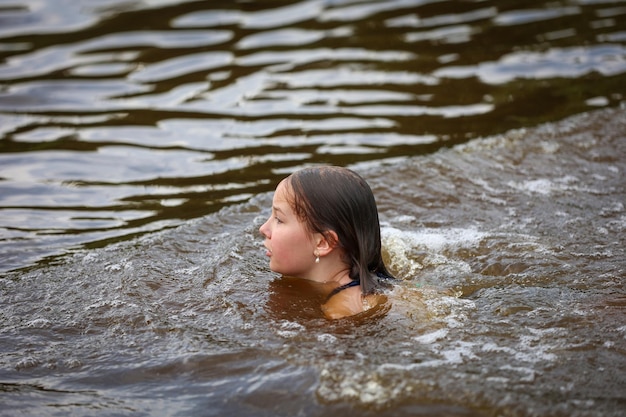 Una niña nada en el río en un caluroso día de verano.