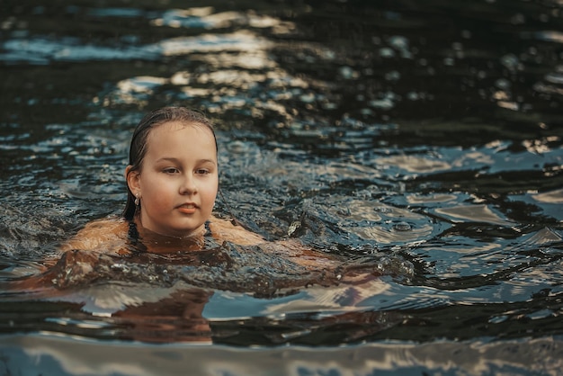 Una niña nada en el río en un caluroso día de verano.