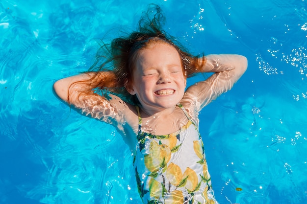 Niña nadando en la piscina en verano