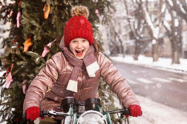 La niña de Navidad que se divierte entrega un gran árbol de Navidad a las vacaciones en el invierno nevado.