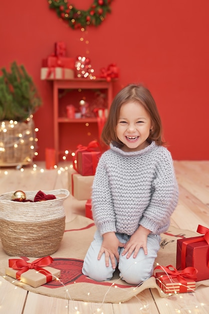 Niña de Navidad con regalos cerca del árbol de Navidad