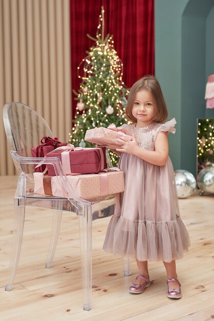 Niña de Navidad con regalos cerca del árbol de Navidad