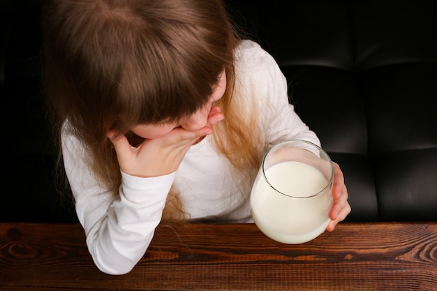 Foto la niña se niega a beber leche de un vaso, se tapa la boca con la mano.