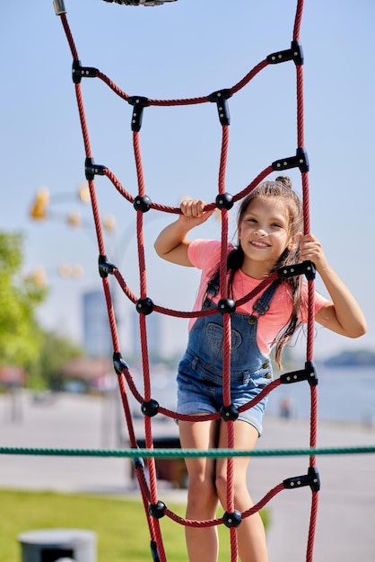 Niña niña divirtiéndose en el patio de recreo en un día soleado