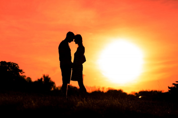 Niña y niño se abrazan en un cielo al atardecer