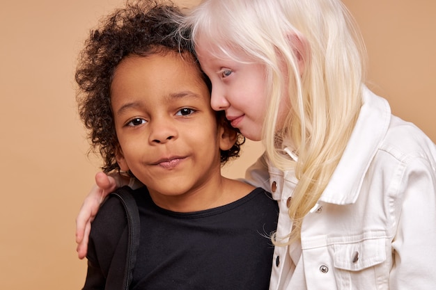 Niña niño albino sensible abrazos niño africano aislado