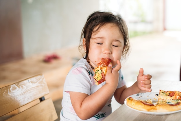 Una niña un niño en la calle come una mini pizza muy apetecible