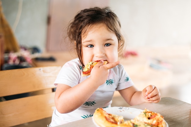 Una niña un niño en la calle come una mini pizza muy apetecible