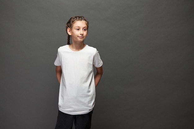 Niña niño con camiseta blanca con espacio para su logotipo o diseño en estudio sobre fondo gris