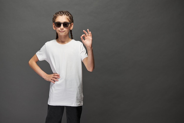 Niña niño con camiseta blanca con espacio para su logotipo o diseño en estudio sobre fondo gris