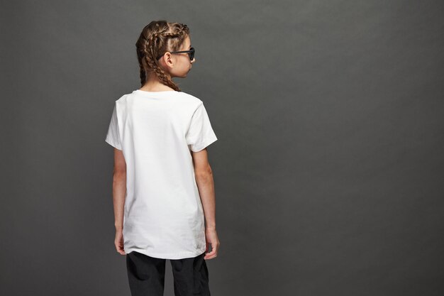 Niña niño con camiseta blanca con espacio para su logotipo o diseño en estudio sobre fondo gris