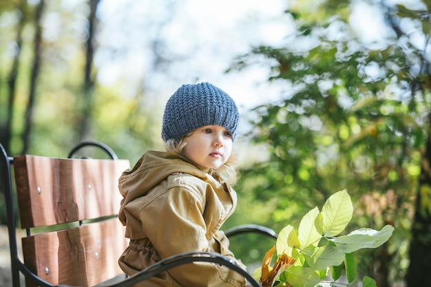 Niña niño en chaqueta y sombrero en el otoño en el parque