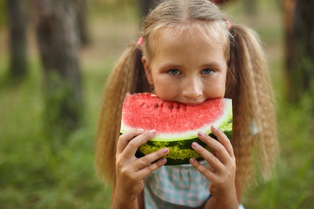 Niña niño comiendo sandía en el jardín.