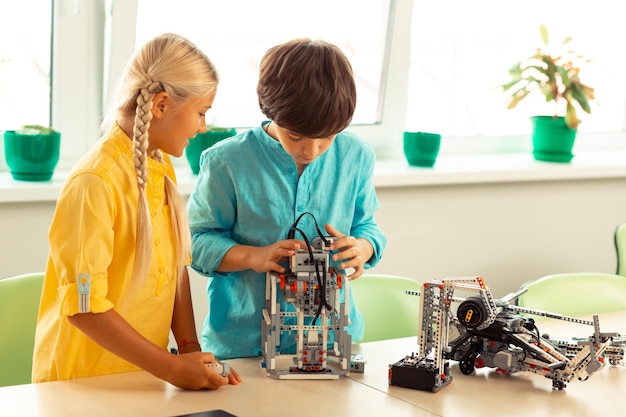 Niña y niño construyendo juntos un pequeño robot