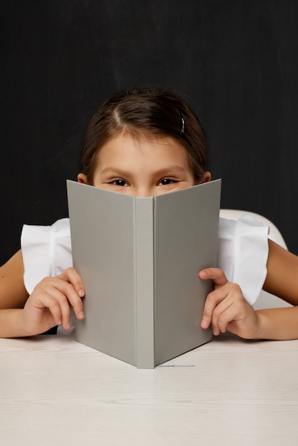 Niña niño cubre su rostro por el libro