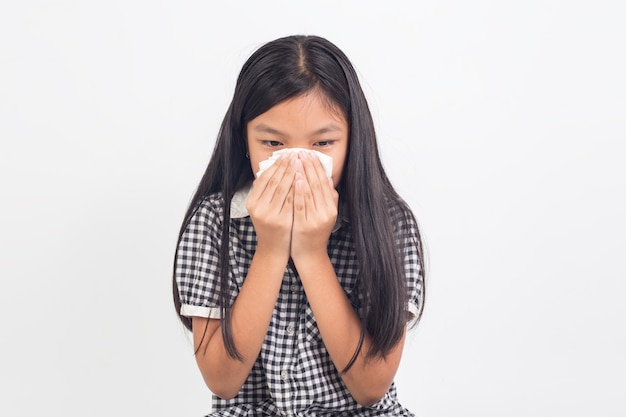 Niña niño enfermo sonándose la nariz aislado en blanco