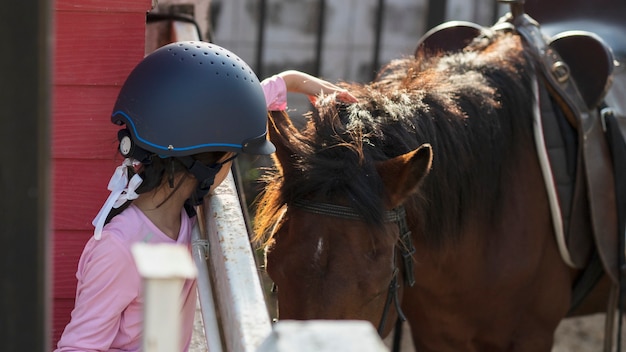 Niña de niño de escuela asiática con caballo, montar a caballo o practicar paseos a caballo en el rancho de caballos.