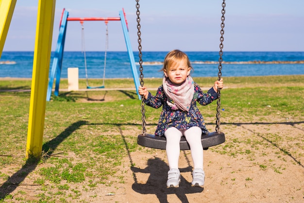 Niña niño feliz en columpio en día de verano