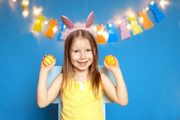 Niña niño feliz divertido con huevos de Pascua sobre fondo azul.