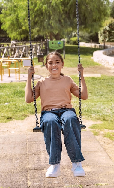 Niña niño feliz divirtiéndose con columpio de cadena en el patio de recreo en un parque. Niño lindo disfrutando de tiempo al aire libre en verano. Concepto de actividad al aire libre de verano, auténtico momento infantil. Maqueta de camiseta