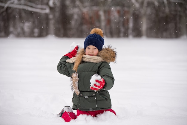 Niña niño feliz plaing con nieve en un paseo de invierno cubierto de nieve