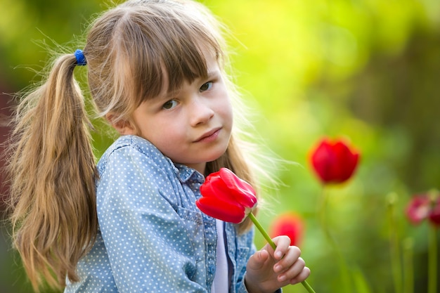 Niña niño con flor de tulipán rojo brillante