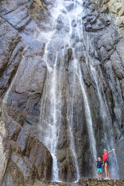 Una niña con un niño en el fondo de la cascada AbaiSu KabardinoBalkaria junio de 2021