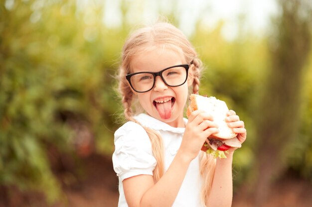 Niña niño gracioso comiendo sándwich al aire libre