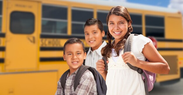 Niña y niño hispanos caminando cerca del autobús escolar