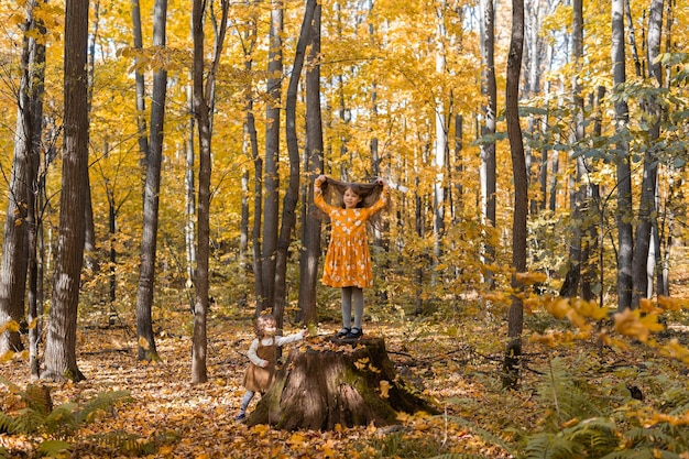 Niña niño con hojas de naranja otoñal en un concepto de temporada de otoño y niños de estilo de vida de parque