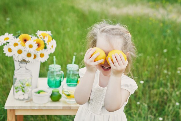 Niña niño con limonada. Flores de limonada y Margarita en la mesa.