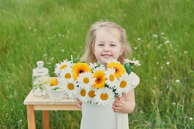 Niña niño con limonada. Flores de limonada y Margarita en la mesa.