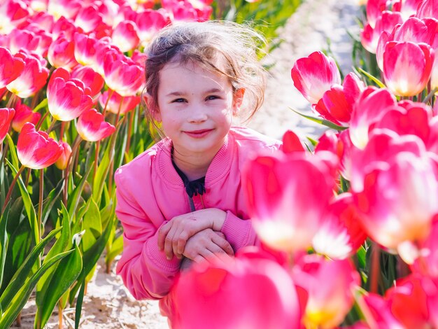 Niña niño lindo con el pelo largo en campos de tulipanes