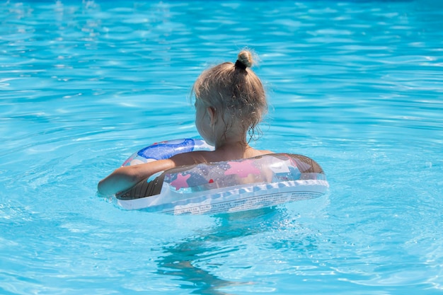 Niña niño nada con un anillo inflable en la piscina