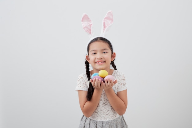 Niña niño con orejas de conejo de Pascua con huevo