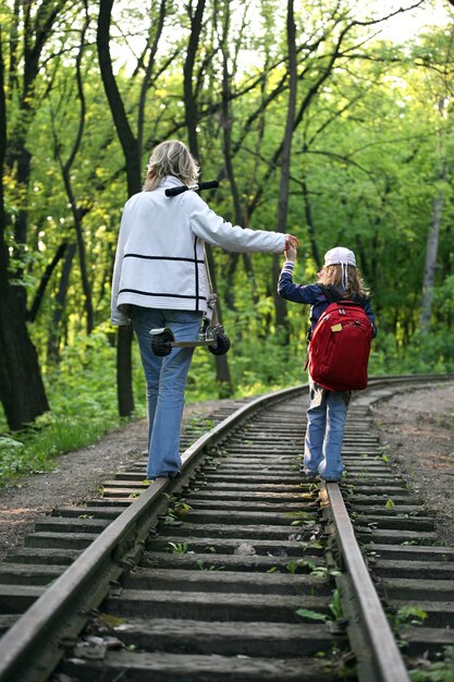 Niña con un niño pequeño caminando sobre las vías del tren