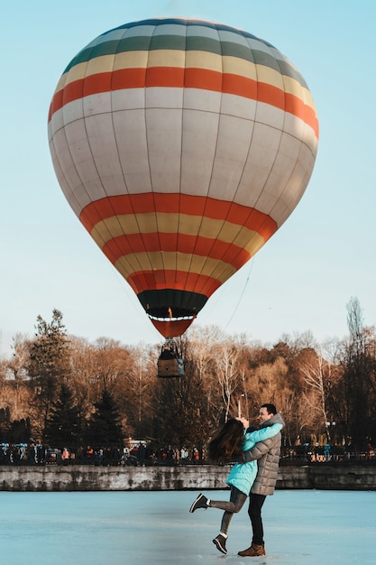 Una niña con un niño de pie sobre el hielo con el telón de fondo de un globo en el parque.