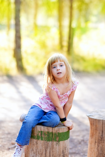 niña niño rubio en el bosque de tronco de árbol