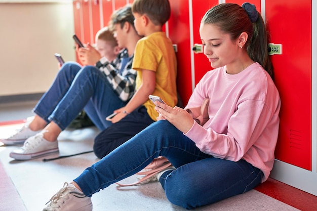 Niña y niño sentados con el teléfono inteligente