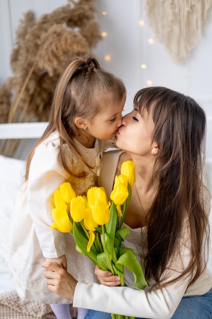 Una niña de un niño con su madre abraza y besa dando un ramo de tulipanes amarillos Estilo de vida Flores frescas Día Internacional de la Mujer o Día de la Madre Fotografía de alta calidad