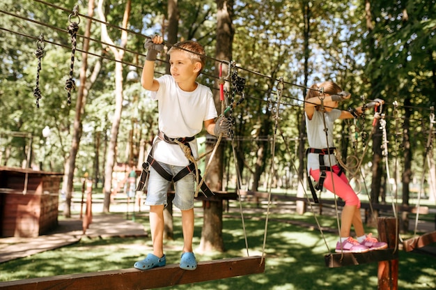 Niña y niño sube en el parque de cuerdas