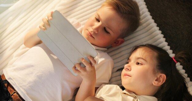 Niña y niño con tabletas digitales