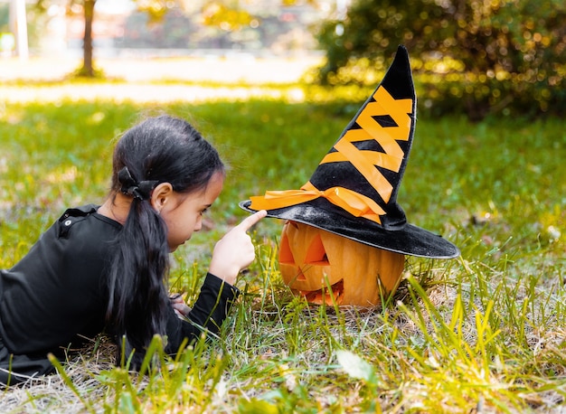 Niña y niño talla de calabaza en Halloween. Niños disfrazados de truco o trato. Truco o trato de los niños. Niño disfrazado de bruja jugando en el parque otoño. Niño pequeño con jack-o-lantern.