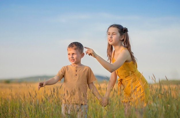 una niña y un niño se toman de la mano y se paran en un campo